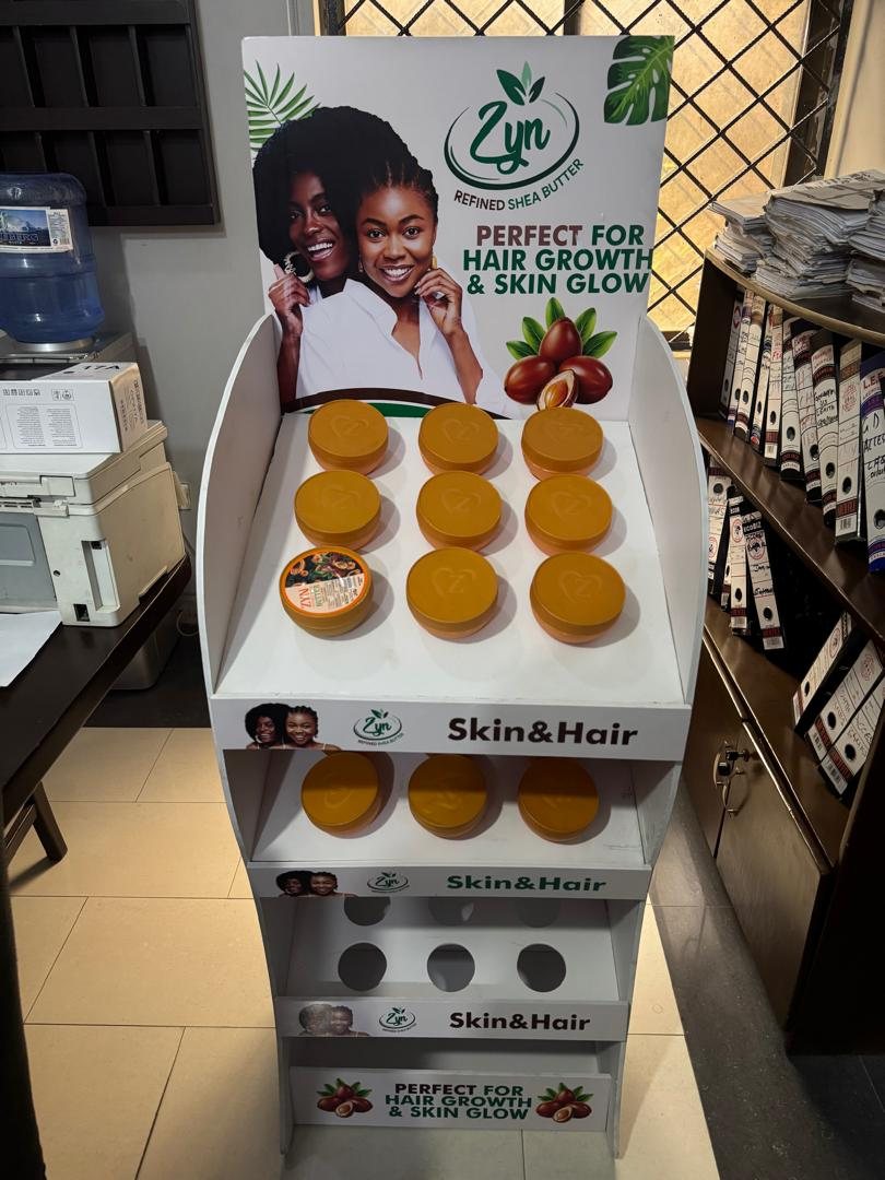 A white Zyn Refined Shea Butter floor stand filled with tubs of shea butter.