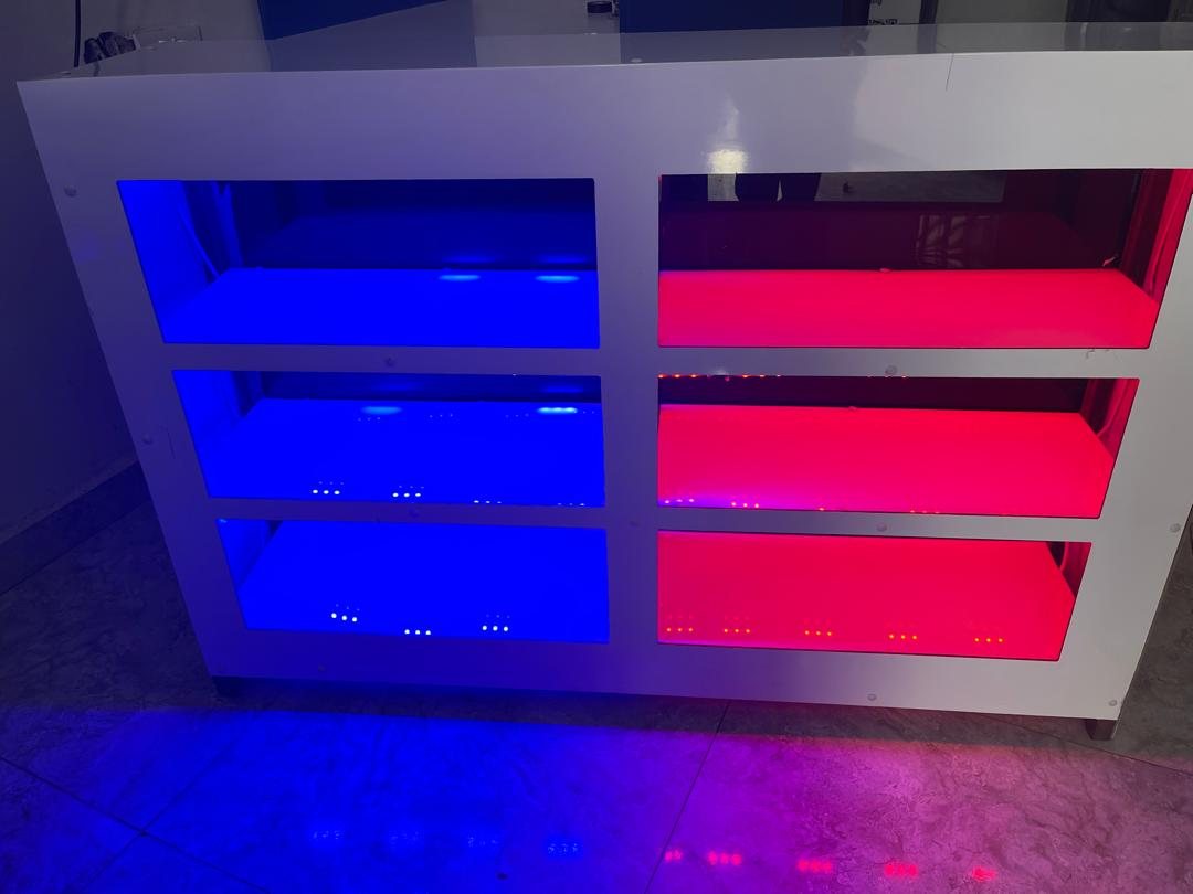 A white counter unit with six shelves lit in blue and red by built in LEDs.