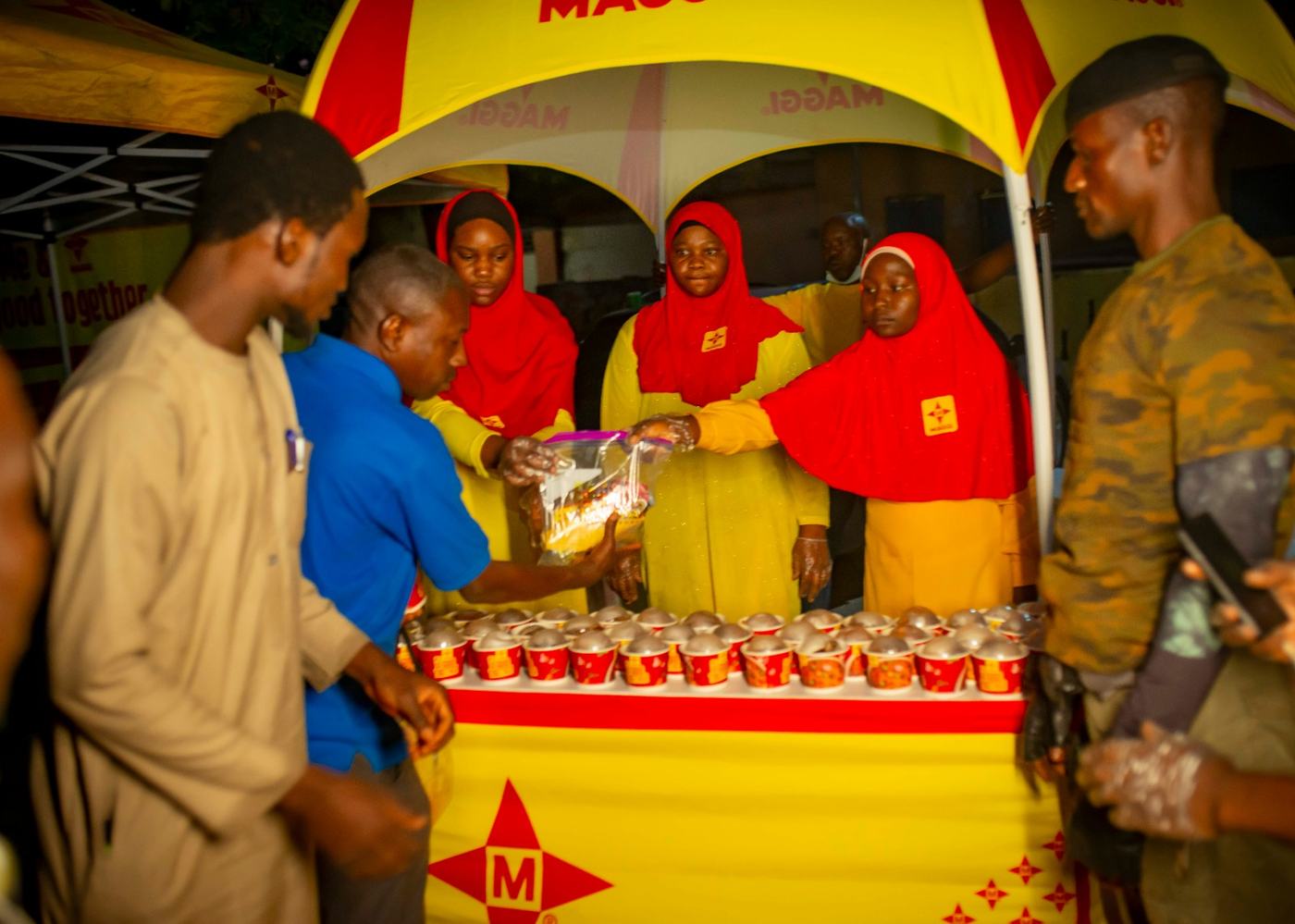 A busy counter with several people being served portions at the branded booth.
