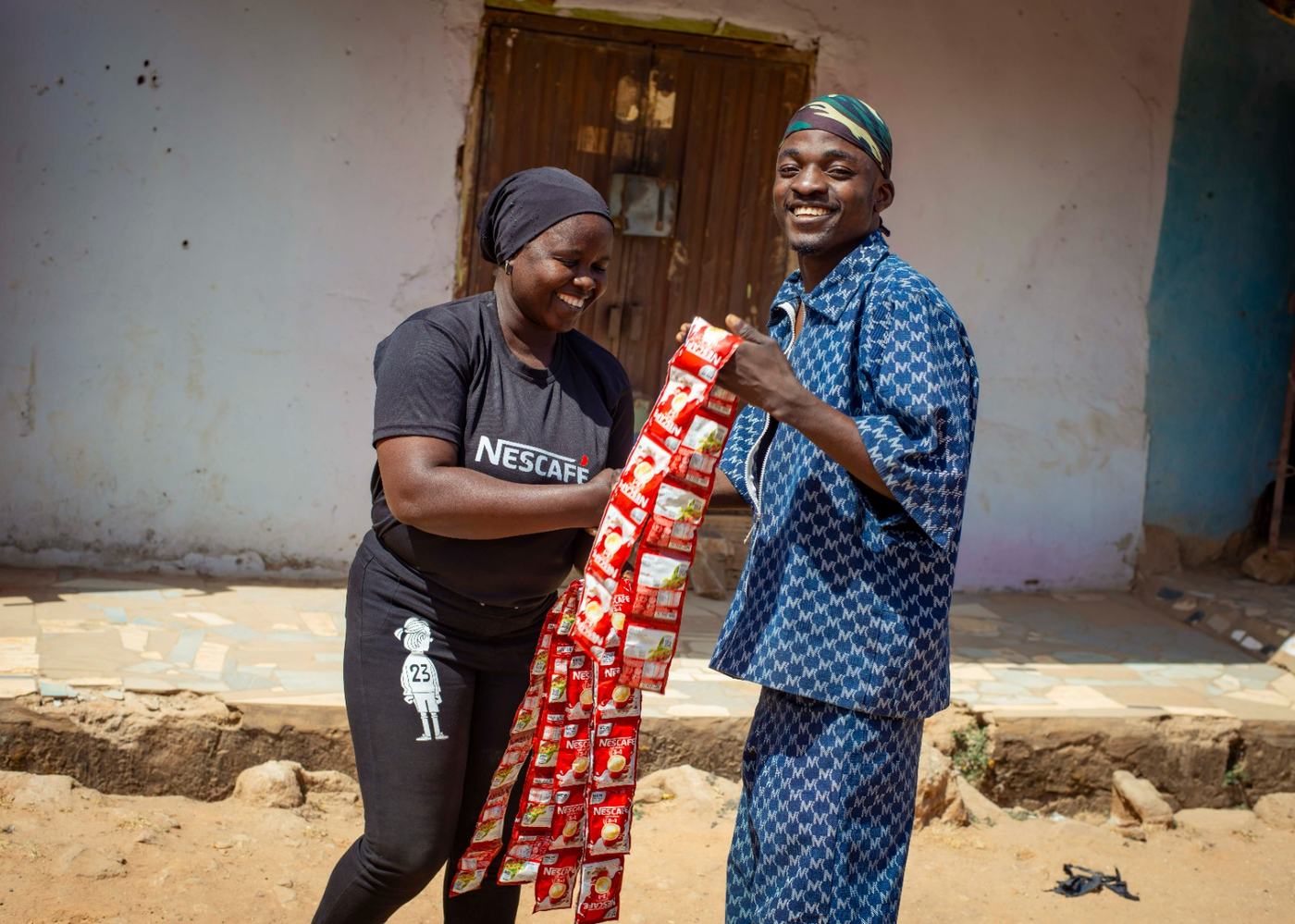 A smiling resident receiving a strip of Nescafe sachets from an ambassador at his door.
