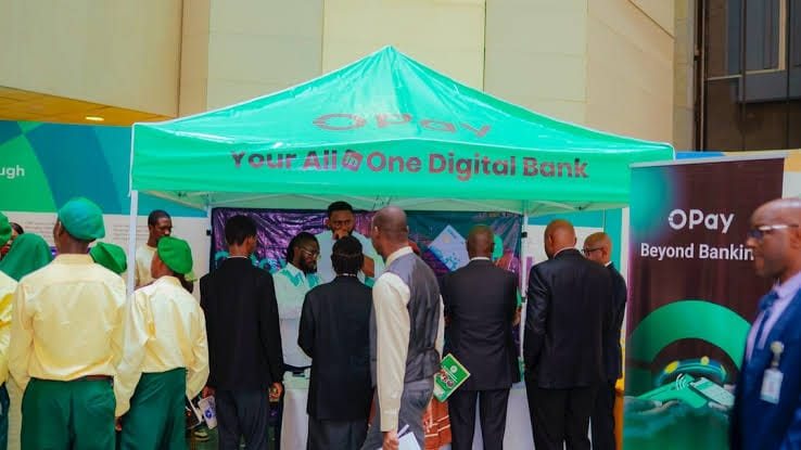 An OPay canopy reading Your All In One Digital Bank with a crowd around it.