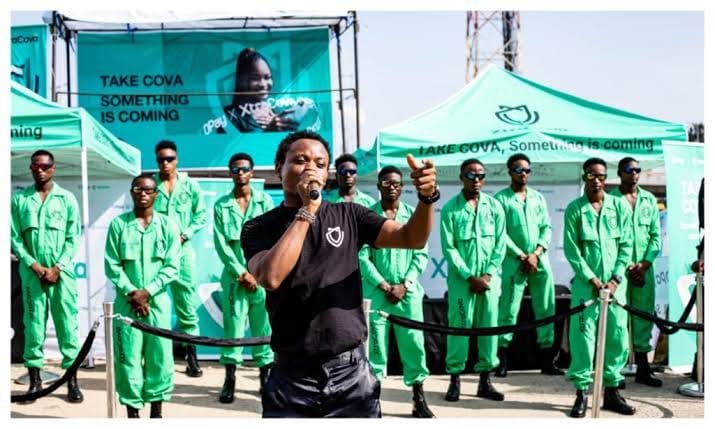 A host with a microphone in front of brand ambassadors in green coveralls.