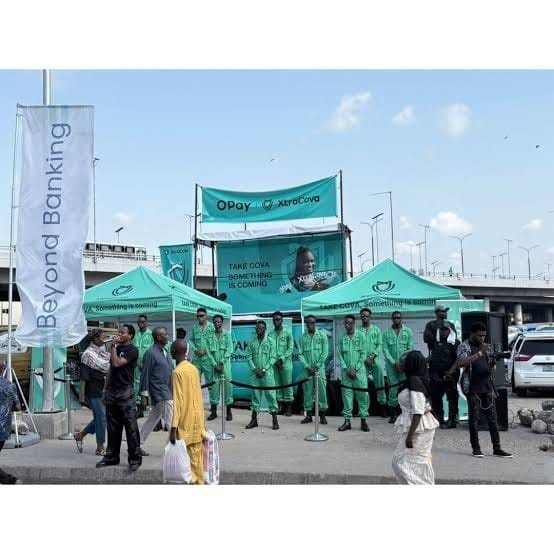 OPay canopies, a truck stage and a line of ambassadors beside a busy road.